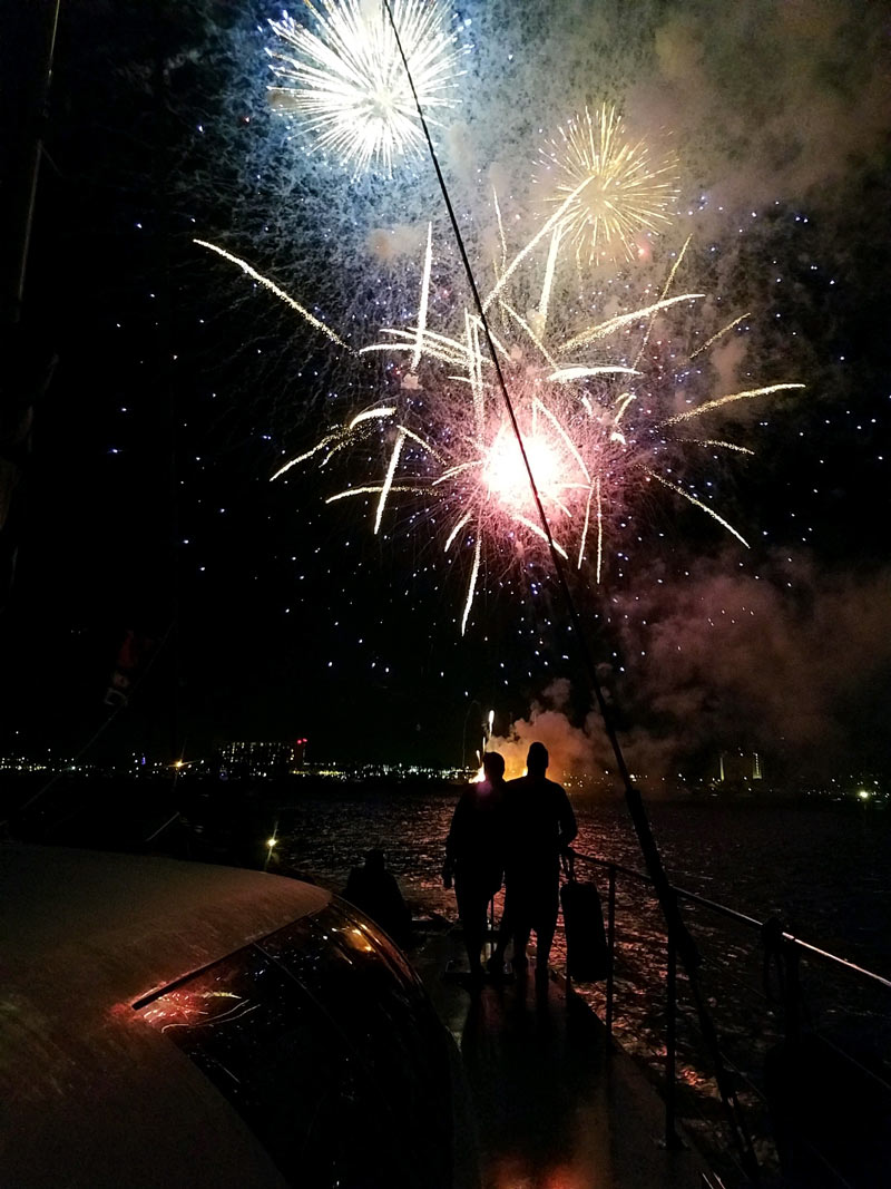 people watching fireworks go off while they are on a catamaran